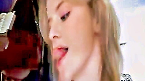 Closeup of seductive blonde babe with pink tongue extended and lips parted teasingly near piano.