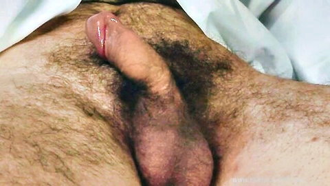 Hairy man's erect cock exposed under sheets in enema scene