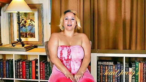 Curvy blonde MILF in pink tie-dye dress smiling playfully