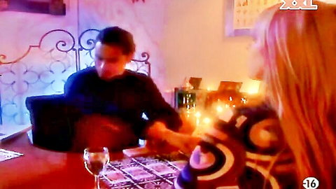 Sensual redhead leans close to man at candlelit dinner table teasing foreplay