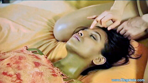 Sensual Indian beauty lying on bed with hand caressing her lips and face passionately