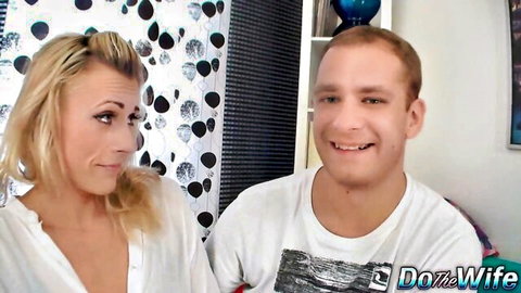 Blonde MILF smiles showing deep cleavage next to smiling cuckold husband