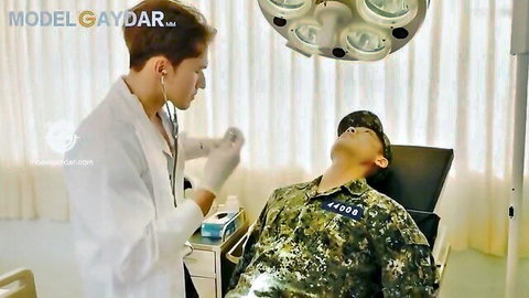 Asian doctor in white coat examines fit military patient in camo uniform during erotic medical checkup