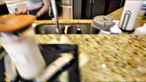Blonde MILF in tight top washes dishes at kitchen sink with sexy white-socked leg visible POV
