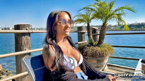 Zoey Sinn in revealing snake print bikini top, lounging seaside