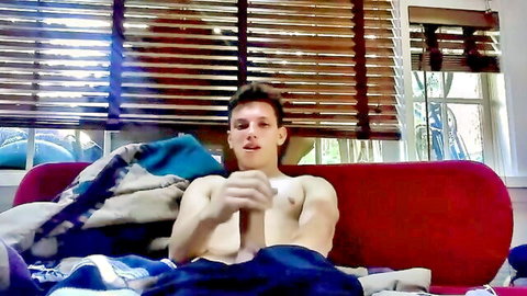 Shirtless muscular webcam boy with XI IX X tattoo on couch