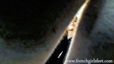 Blonde French girl peeking seductively through dark curtains on foot fetish site