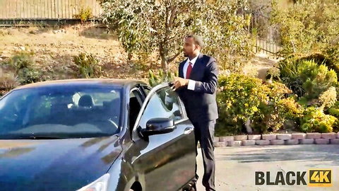 Suited black man in suit leaning into open car door outdoors teasing BBC