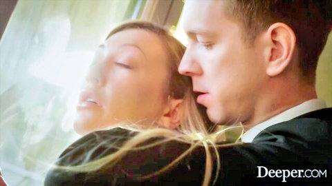 Blonde beauty in ecstasy passionately embraced by suited man against window