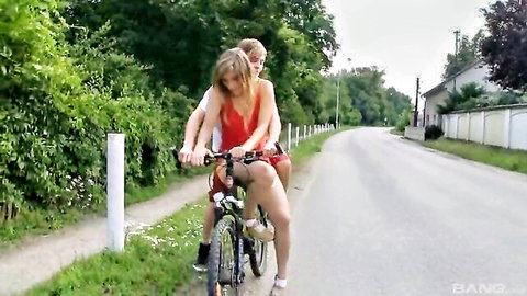 Two blondes in short skirts biking outdoors, teasing asses