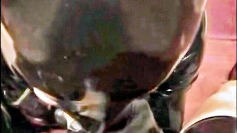 Black latex-clad man intensely sucking thick white cock in gay blowjob closeup