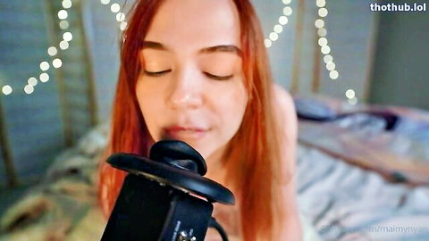 Topless redhead with long hair sensually kisses black microphone eyes closed ASMR style
