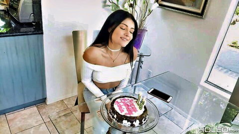Brunette babe smiling with eyes closed holding birthday cake in off-shoulder white top