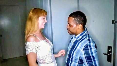 Smiling blonde in sexy lace top flirts intimately with black man in hallway