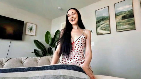 Dolly Paige in cherry slip dress, smiling teasingly on couch