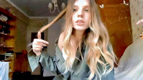 Skinny blonde teen webcam girl teasing in off-shoulder top holding up her long wavy hair