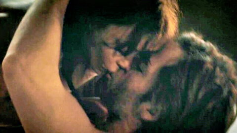 Brunette mature woman passionately kissing bearded man in intense closeup embrace