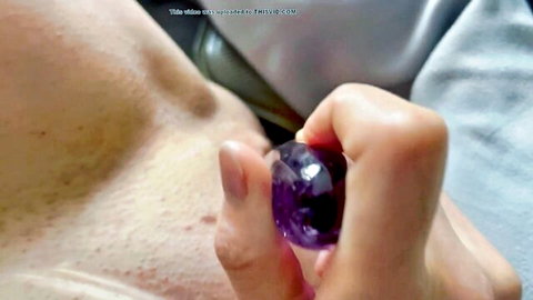 Blurry closeup of hand gripping purple crystal gem against hairy male chest