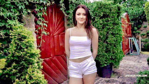 Alya Stark smiling in white tank top and short shorts, outdoor tease