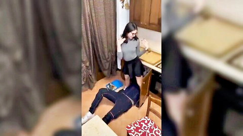 Brunette in skirt stands over plumber on floor in steamy kitchen hookup