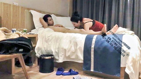 Chinese MILF with bun sucking naked man's cock on hotel bed