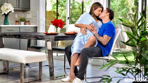 Pregnant brunette MILF in light blue dress passionately kissing tattooed guy on his lap