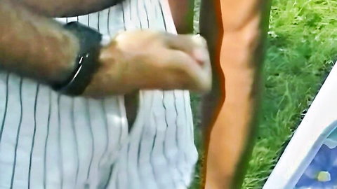 Man groping tanned woman's thigh outdoors with open fly on striped shorts