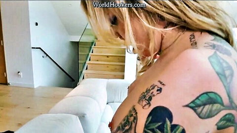 Blonde tattooed babe with huge tits leaning over white couch in POV