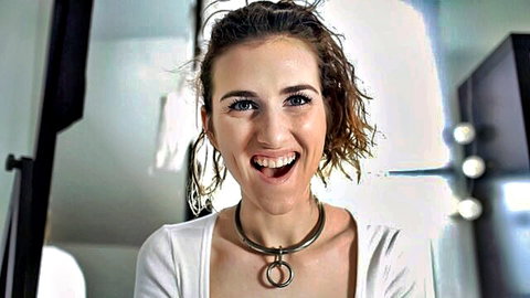 Fair-skinned curly-haired babe smiles wide with open mouth wearing BDSM metal collar