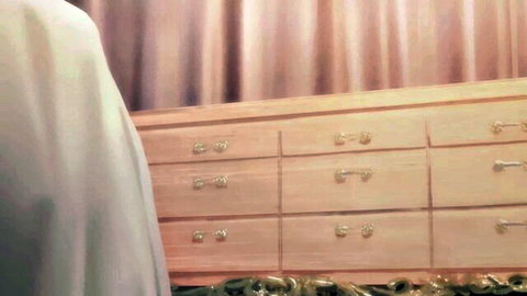Mystery woman in flowing white dress posing seductively near wooden furniture