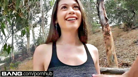 Smiling brunette teen in black tank top teasing in eucalyptus forest outdoors