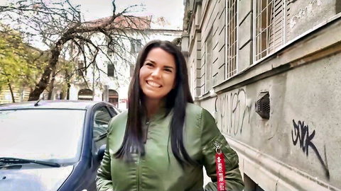 Voluptuous brunette smiling in green bomber jacket at German casting