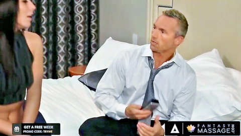 Asian masseuse in black top seduces suited man on bed in erotic massage scene