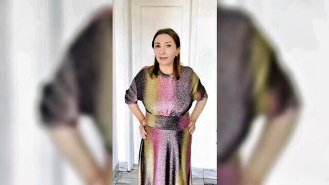 Sexy mature MILF in shiny multicolored sequin dress posing with hands on hips indoors