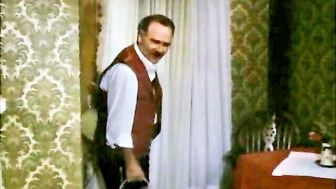 Vintage 1974 softcore scene: mustached older man in white shirt and brown vest holding briefcase