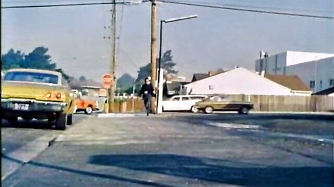 Vintage 1977 Foxy Lady street scene with classic cars and man walking