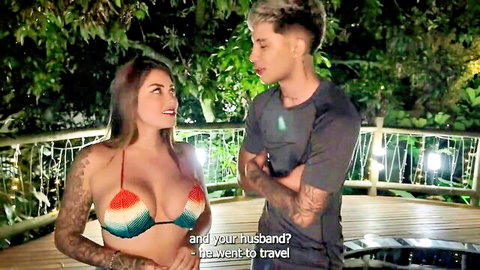 Tattooed curvy woman in rainbow bikini with fit guy on jungle balcony