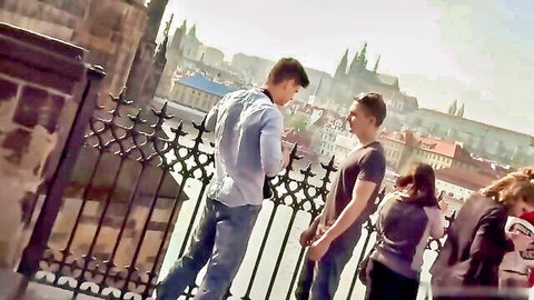 Two fit guys chatting on Prague bridge overlook, teasing gay anal action