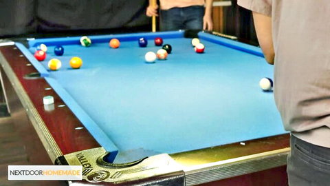 Two muscular young men playing pool on blue table in bar