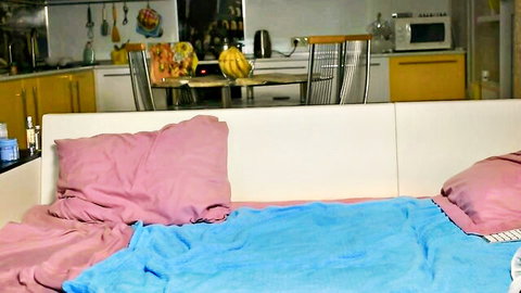 Homemade webcam show setup on bed with pink pillows and blue blanket