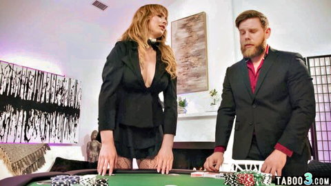 Busty blonde in deep V black suit leans over poker table teasing with bearded suited man in taboo game