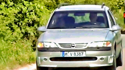 Silver German Opel car on rural road surrounded by green bushes