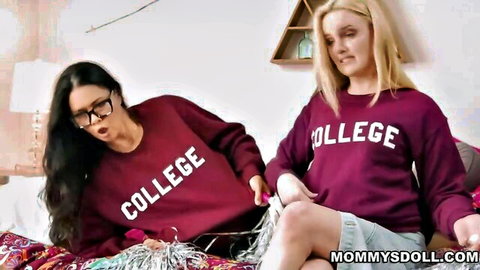 Two college girls in matching maroon COLLEGE sweatshirts teasing on bed with garland