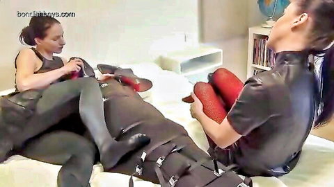 Leather-clad dominatrix with bound submissive in shoe sniffing BDSM therapy session