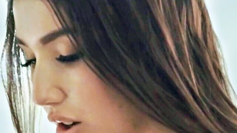 Close-up of seductive brunette with long hair, heavy lashes, and parted glossy lips