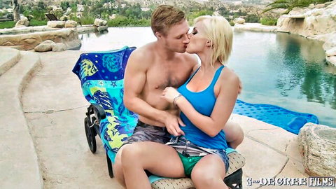 Blonde couple passionately kissing poolside, her in tight blue tank top and shorts on his lap