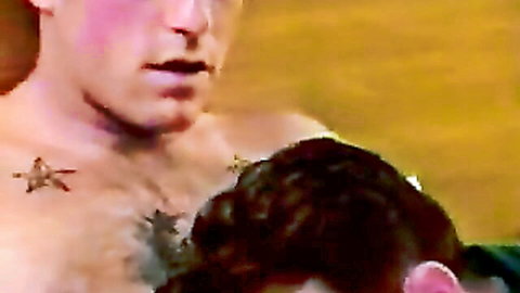 Two hairy men in close intimate pose, chest tattoos visible
