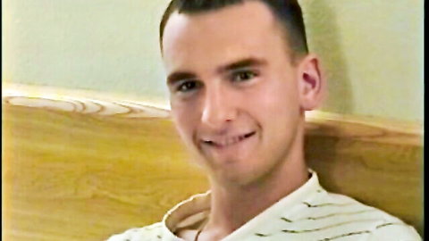 Smiling young Caucasian man in striped shirt on bed
