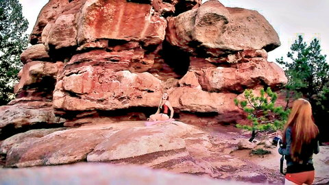 Redhead babe in orange shorts photographs naughty blonde in pink bikini posing in red rock cave outdoors