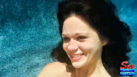 Stunning dark-haired beauty smiling topless in pool from sex tapes